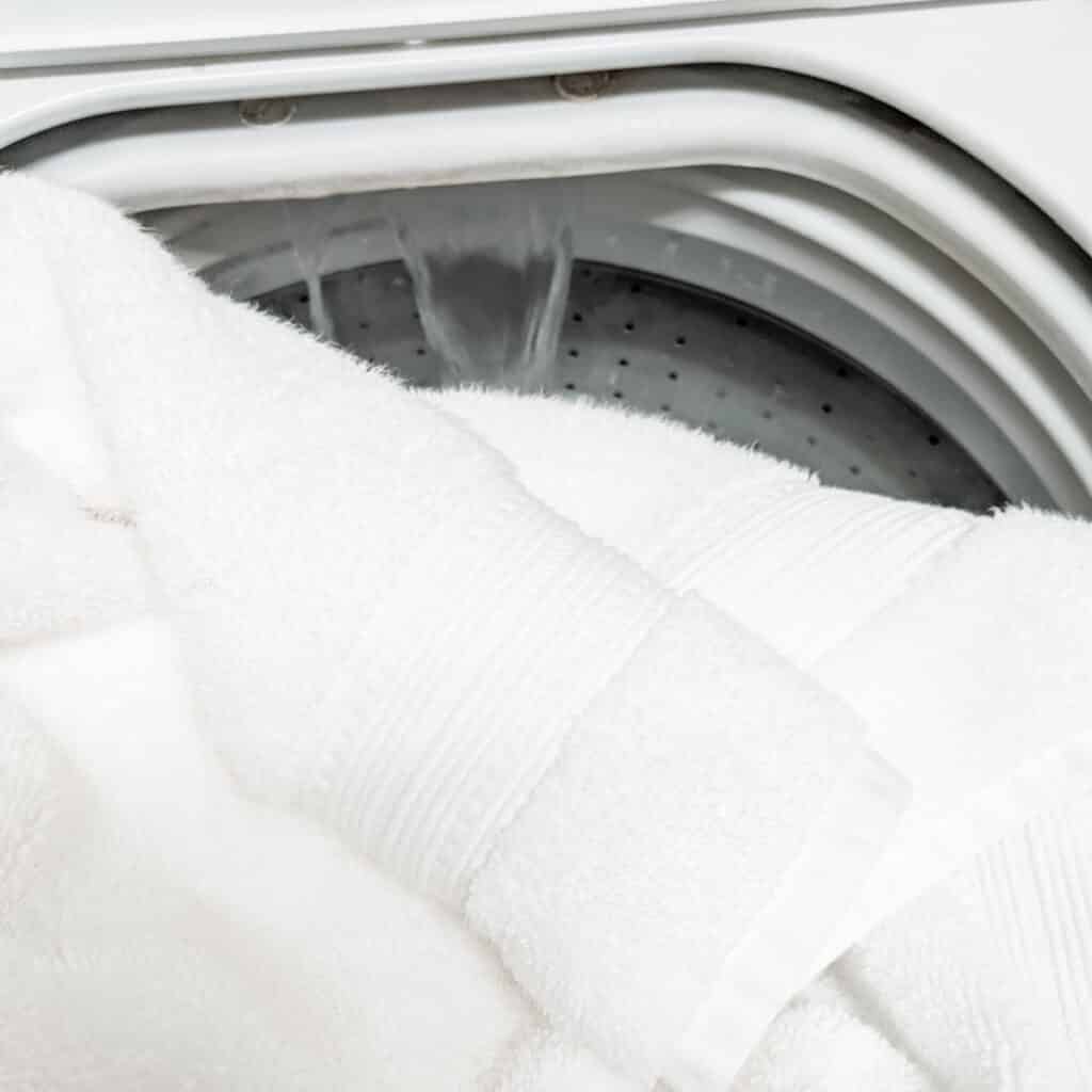 Filling the washing machine with hot water and adding towels in.