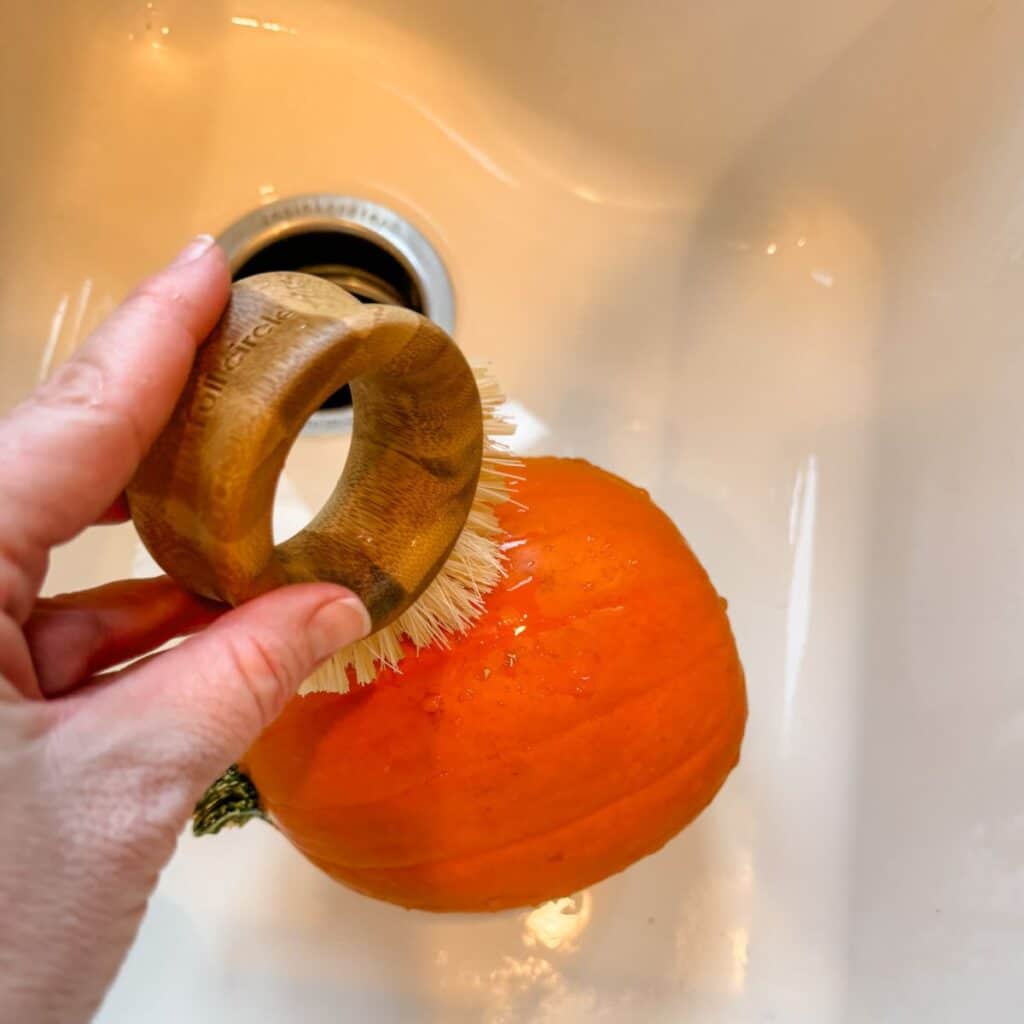 scrubbing pumpkin in the sink to clean it