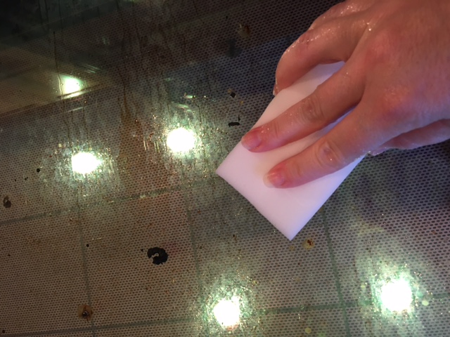 Wiping the oven door glass with a magic eraser.