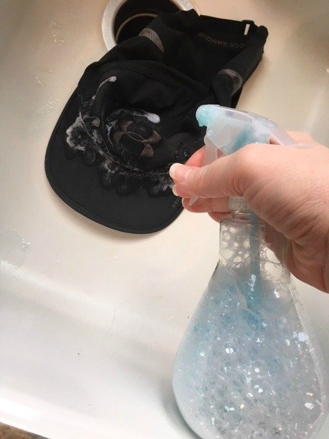 Spraying the dirty cap with the cleaning solution.