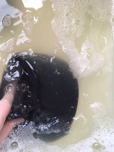 washing ball cap in a sink of water.