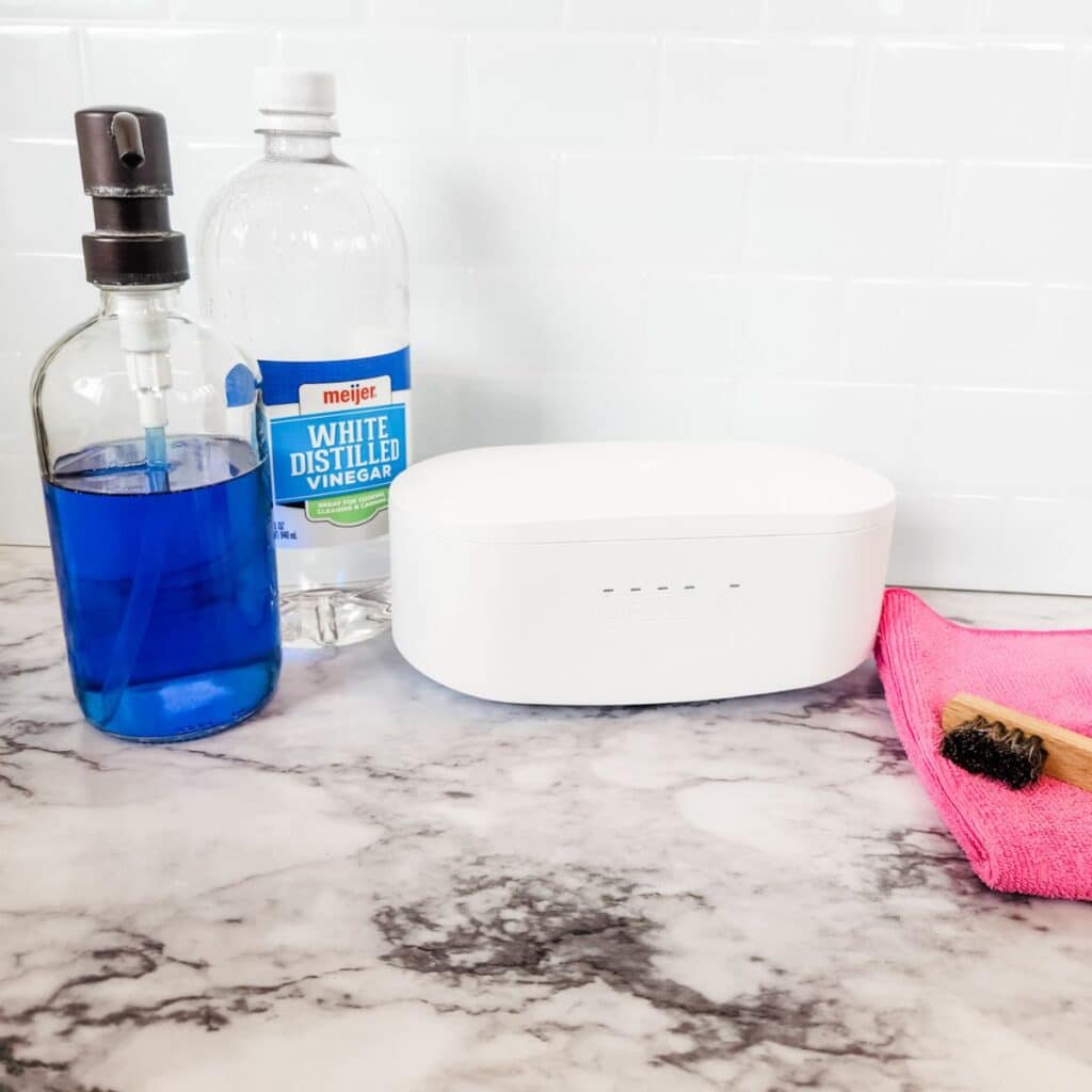 DIY homemade jewelry cleaner in a bottle next to a jewelry ultrasonic machine and soft bristle brush