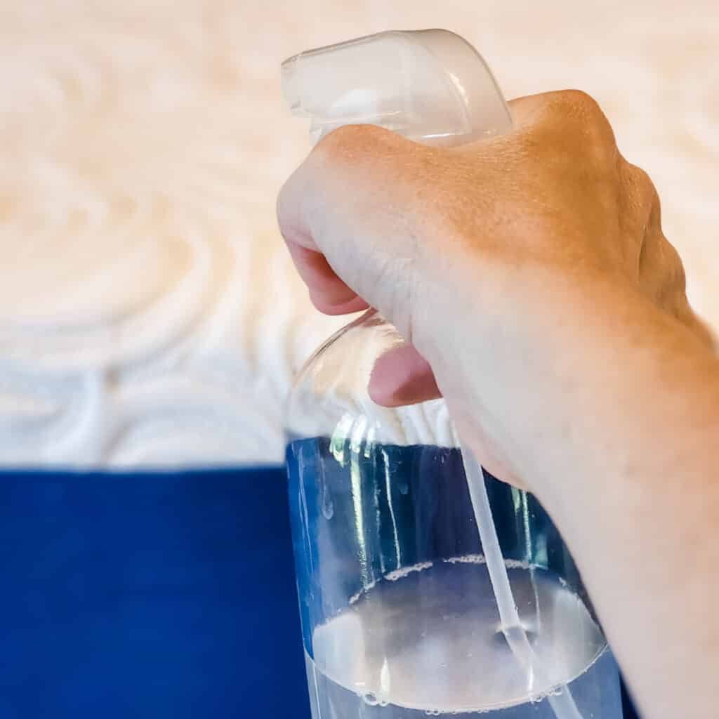 spraying a memory foam mattress with dust mite spray