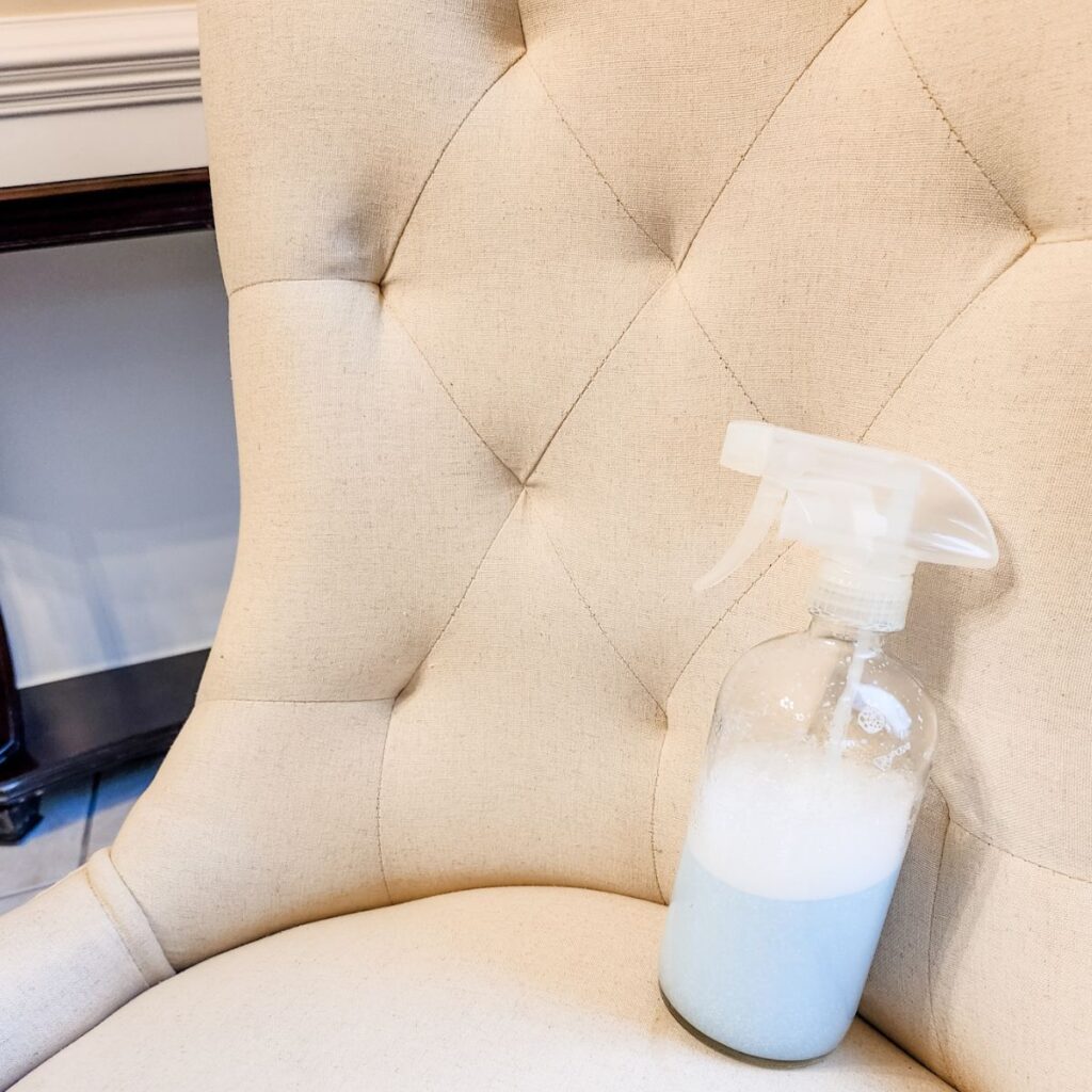 A bottle of my DIY upholstery cleaner sitting on white chair.