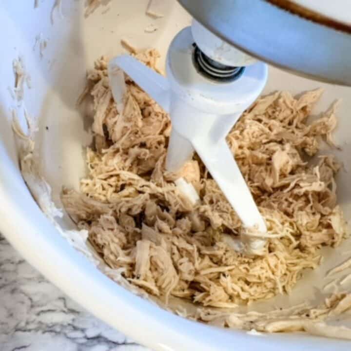 chicken breasts being shredded in a mixer